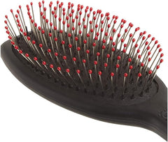 A close-up of a black paddle hairbrush with metal bristles tipped in red, shown against a plain white background.