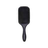 A black Denman paddle hairbrush with a wide, rectangular head and a tapered handle, centered against a clean white square background within a dark digital interface layout.
