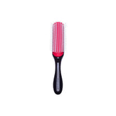 A classic Denman hairbrush with a black handle, a bright red pad, and white nylon bristles, centered on a plain white background.