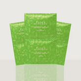Three green Rose & Caramel Purity Q soft gels in pouches, arranged in a fan-like composition on a light gray background with a soft reflection below.