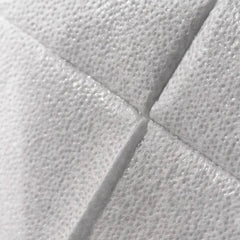 Close-up of a white textured material with a quilted or padded geometric pattern and stitched panel lines.