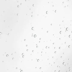 A close-up of a clear liquid with numerous small, scattered water droplets on a light gray-white background.